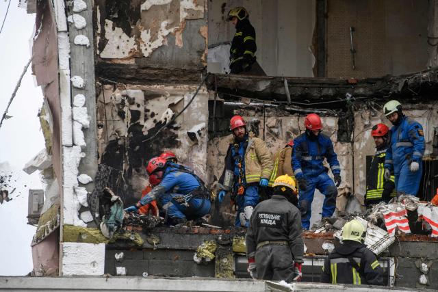 Ukrainian rescuers recover a victim's body from the rubble of a damaged residential building following Russian drones and missiles attack in Kyiv, on December 27, 2025, amid the Russian invasion in Ukraine. Russia pummelled Ukraine's capital with drones and missiles on December 27, killing a woman and cutting power to hundreds of thousands, ahead of the latest talks between the presidents of Ukraine and the US. (Photo by VLADYSLAV MUSIENKO / AFP)