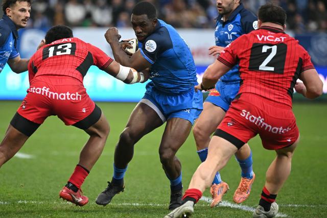 Castres' Cameroonian wing Christian Ambadiang (C) breaks through a tackle during the French Top 14 rugby union match between Castres Olympique and Lyon Olympique Universitaire Rugby (LOU) at Stade Pierre Fabre in Castres, southern France, on December 27, 2025. (Photo by Matthieu RONDEL / AFP)