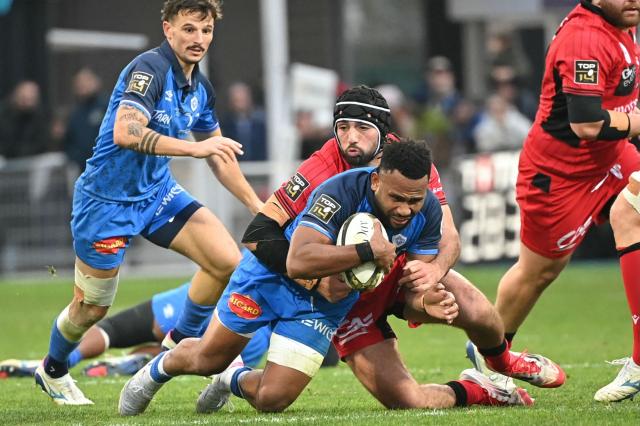 Castres' Fijian centre Vilimoni Botitu (C) is tackled during the French Top 14 rugby union match between Castres Olympique and Lyon Olympique Universitaire Rugby (LOU) at Stade Pierre Fabre in Castres, southern France, on December 27, 2025. (Photo by Matthieu RONDEL / AFP)