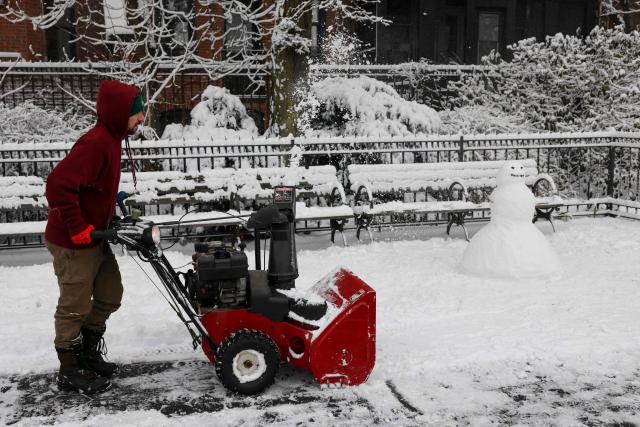 A worker clears a path of snow in New York City on December 27, 2025. New York City receieved around 4 inches (10 centimeters) of snow overnight. Airlines canceled 1,500 US flights during the peak holiday travel period Friday, with severe winter storm warnings and heavy snow forecast across parts of the Midwest and northeast. (Photo by ANGELA WEISS / AFP)