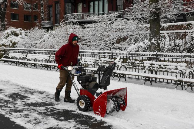 A worker clears a path of snow in New York City on December 27, 2025. New York City receieved around 4 inches (10 centimeters) of snow overnight. Airlines canceled 1,500 US flights during the peak holiday travel period Friday, with severe winter storm warnings and heavy snow forecast across parts of the Midwest and northeast. (Photo by ANGELA WEISS / AFP)