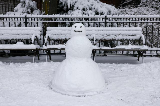 A snowman stands near a park bench in New York City on December 27, 2025. New York City receieved around 4 inches (10 centimeters) of snow overnight. Airlines canceled 1,500 US flights during the peak holiday travel period Friday, with severe winter storm warnings and heavy snow forecast across parts of the Midwest and northeast. (Photo by ANGELA WEISS / AFP)