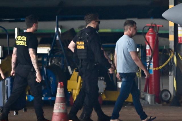 Silvinei Vasques (R), former director of Brazil's Federal Highway Police, arrives at Juscelino Kubitschek International Airport escorted by Federal Police agents in Brasilia on December 27, 2025, after being handed over by Paraguayan authorities. Vasques was arrested in Asuncion on December 26 while attempting to board a flight to El Salvador in an effort to escape after being sentenced by the Brazilian Supreme Court to 24 years in prison for taking part in an attempted coup d'état. (Photo by Evaristo Sa / AFP)