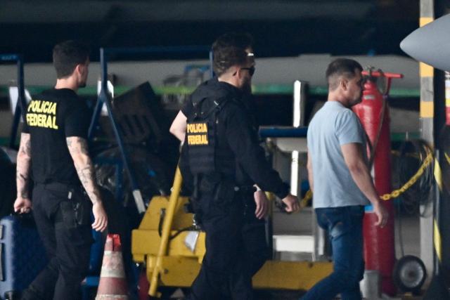 Silvinei Vasques (R), former director of Brazil's Federal Highway Police, arrives at Juscelino Kubitschek International Airport escorted by Federal Police agents in Brasilia on December 27, 2025, after being handed over by Paraguayan authorities. Vasques was arrested in Asuncion on December 26 while attempting to board a flight to El Salvador in an effort to escape after being sentenced by the Brazilian Supreme Court to 24 years in prison for taking part in an attempted coup d'état. (Photo by Evaristo Sa / AFP)