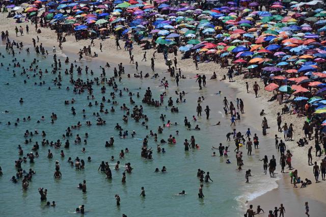 People enjoy Recreio dos Bandeirantes beach, in the southwest zone of Rio de Janeiro, Brazil, on December 27, 2025. (Photo by TERCIO TEIXEIRA / AFP)