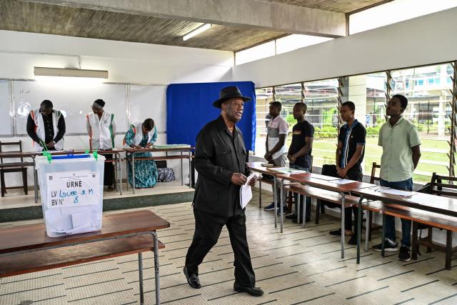 Ivory Coast's President Alassane Ouattara walks to the voting booth to cast his ballot at a polling station at the Lycee Saint-Marie in Cocody, the residential district of Abidjan on December 27, 2025 during Ivory Coast's legislative elections. (Photo by Sia KAMBOU / AFP)