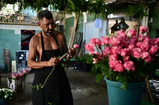 Jackson Soares, 56, works shirtless as he prepares flowers inside his flower shop in the Guaratiba neighborhood of Rio de Janeiro, Brazil on December 27, 2025. (Photo by TERCIO TEIXEIRA / AFP)