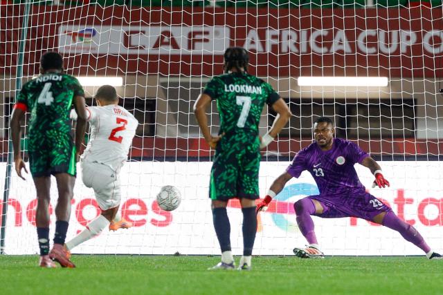 Tunisia's defender #02 Ali Abdi scores a goal on a penalty in front of Nigeria's goalkeeper #23 Stanley Nwabali during the Africa Cup of Nations (CAN) Group C football match between Nigeria and Tunisia at Fez Stadium in Fez on December 27, 2025. (Photo by Abdel Majid BZIOUAT / AFP)