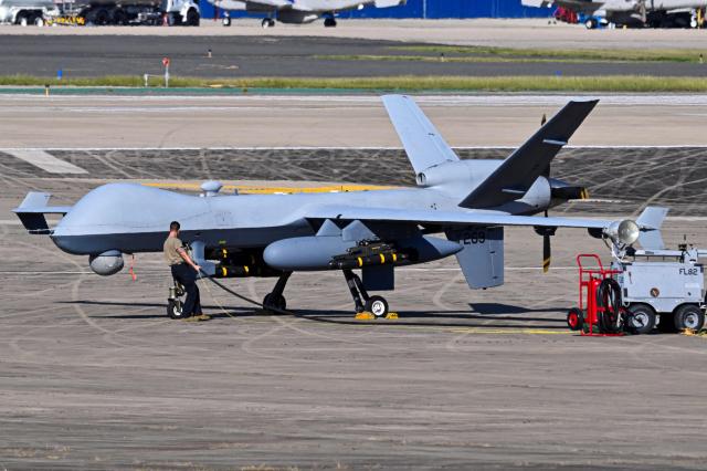 A US Air Force personnel prepares an MQ-9 Reaper drone for a mission on the tarmac at Rafael Hernandez Airport in Aguadilla, Puerto Rico, on December 27, 2025. The United States has deployed a major military force in the Caribbean and has recently intercepted oil tankers as part of a naval blockade against Venezuelan vessels it considers to be under sanctions. Since September, US forces have launched dozens of air strikes on boats that Washington alleges, without showing evidence, were transporting drugs. More than 100 people have been killed. (Photo by Miguel J. Rodriguez Carrillo / AFP)