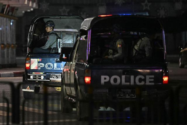 Police officers patrol near a polling station during the first phase of Myanmar's general election in Yangon on December 28, 2025. Voting begins in Myanmar's heavily restricted polls, with the ruling junta touting the exercise as a return to democracy five years after it ousted the last elected government, triggering civil war. (Photo by Lillian SUWANRUMPHA / AFP)