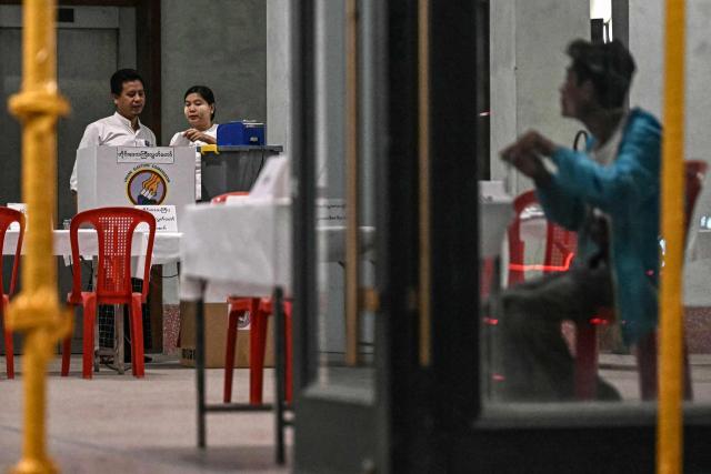Members of Myanmar's Union Election Commission (UEC) set up an electronic voting booth at a polling station during the first phase of Myanmar's general election in Yangon on December 28, 2025. Voting begins in Myanmar's heavily restricted polls, with the ruling junta touting the exercise as a return to democracy five years after it ousted the last elected government, triggering civil war. (Photo by Lillian SUWANRUMPHA / AFP)