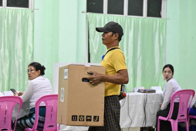 Members of Myanmar's Union Election Commission (UEC) prepare a polling station during the first phase of Myanmar's general election in Yangon on December 28, 2025. Voting begins in Myanmar's heavily restricted polls, with the ruling junta touting the exercise as a return to democracy five years after it ousted the last elected government, triggering civil war. (Photo by NHAC NGUYEN / AFP)