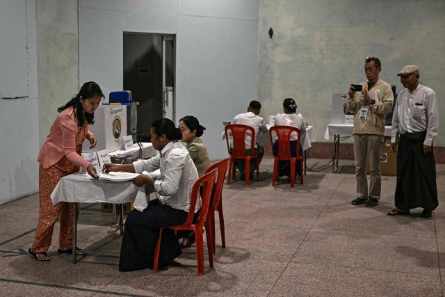 A woman (L) prepares to vote at a polling station during the first phase of Myanmar's general election in Yangon on December 28, 2025. Voting begins in Myanmar's heavily restricted polls, with the ruling junta touting the exercise as a return to democracy five years after it ousted the last elected government, triggering civil war. (Photo by Lillian SUWANRUMPHA / AFP)