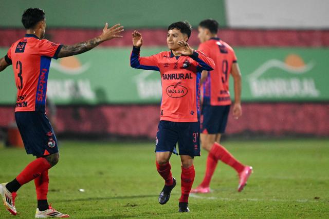 Municipal's midlfielder #31 Cesar Calderon (R) celebrates with teammate Costa Rican defender #03 Jose Mena scoring his team's first goal during the second leg of the Guatemalan Apertura tournament final at El Trebol Stadium in Guatemala City on December 27, 2025. (Photo by JOHAN ORDONEZ / AFP)
