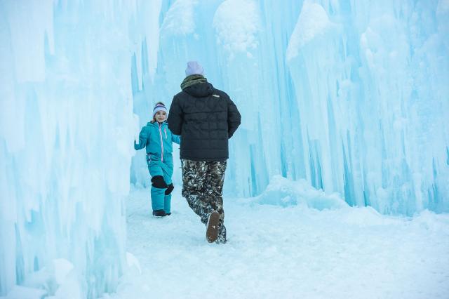 People explore the ice paths and caverns of the Ice Castles during the opening day in North Woodstock, New Hampshire on December 27, 2025. Brent Christensen crafted his first icy creation in the front yard of his home to bring happiness and joy to his children, and since 2011, Ice Castles has been dedicated to creating a world of ice caves, frozen waterfalls, and glaciers formed into archways, caverns, slides, and tunnels. (Photo by Joseph Prezioso / AFP)