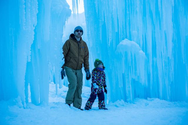 People explore the caverns and tunnels of the Ice Castles during the opening day in North Woodstock, New Hampshire on December 27, 2025. Brent Christensen crafted his first icy creation in the front yard of his home to bring happiness and joy to his children, and since 2011, Ice Castles has been dedicated to creating a world of ice caves, frozen waterfalls, and glaciers formed into archways, caverns, slides, and tunnels. (Photo by Joseph Prezioso / AFP)