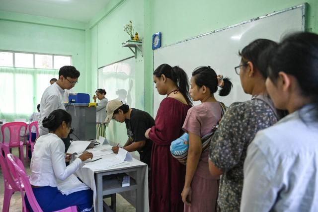 People line up to vote inside a polling station during the first phase of Myanmar's general election in Yangon on December 28, 2025. Polling opened in Myanmar's heavily restricted junta-run elections, beginning a month-long vote democracy watchdogs describe as a rebranding of military rule. (Photo by NHAC NGUYEN / AFP)