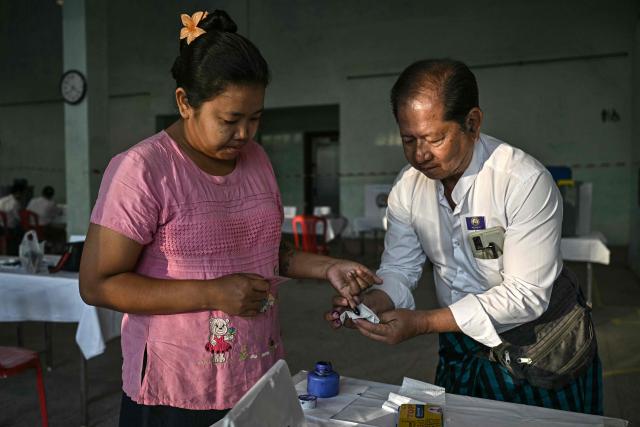 A woman has her finger inked after voting at a polling station during the first phase of Myanmar's general election in Yangon on December 28, 2025. Polling opened in Myanmar's heavily restricted junta-run elections, beginning a month-long vote democracy watchdogs describe as a rebranding of military rule. (Photo by Lillian SUWANRUMPHA / AFP)