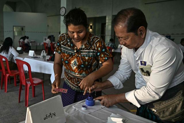 A woman has her finger inked after voting at a polling station during the first phase of Myanmar's general election in Yangon on December 28, 2025. Polling opened in Myanmar's heavily restricted junta-run elections, beginning a month-long vote democracy watchdogs describe as a rebranding of military rule. (Photo by Lillian SUWANRUMPHA / AFP)