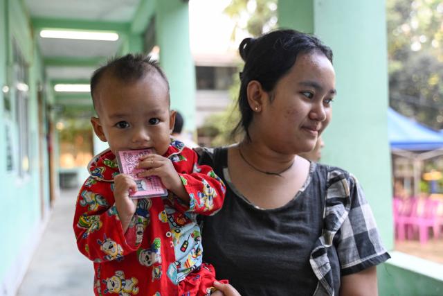 A woman and her child leave after voting at a polling station during the first phase of Myanmar's general election in Yangon on December 28, 2025. Polling opened in Myanmar's heavily restricted junta-run elections, beginning a month-long vote democracy watchdogs describe as a rebranding of military rule. (Photo by NHAC NGUYEN / AFP)