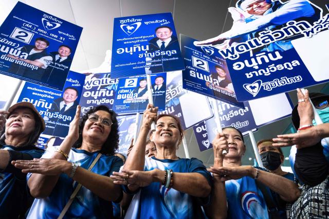 Supporters pose with placards to support Thai prime minister and Bhumjaithai Party leader Anutin Charnvirakul during the first day of the constituencies candidates registration for the upcoming general election, in Bangkok on December 28, 2025. (Photo by Chanakarn Laosarakham / AFP)