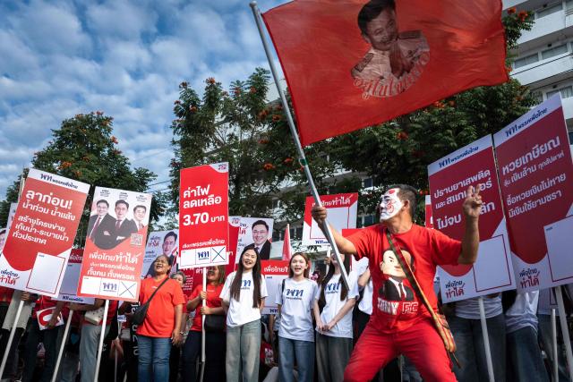 Supporters wave a flag to support the Pheu Thai Party during the first day of the constituencies candidates registration for the upcoming general election, in Bangkok on December 28, 2025. (Photo by Chanakarn Laosarakham / AFP)