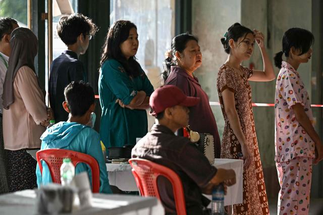People line up to vote inside a polling station during the first phase of Myanmar's general election in Yangon on December 28, 2025. Polling opened in Myanmar's heavily restricted junta-run elections, beginning a month-long vote democracy watchdogs describe as a rebranding of military rule. (Photo by Lillian SUWANRUMPHA / AFP)