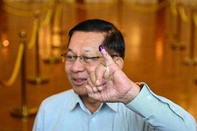 Myanmar's junta chief Min Aung Hlaing shows his inked finger after voting at a polling station during the first phase of Myanmar's general election in Naypyidaw on December 28, 2025. (Photo by Sai Aung MAIN / AFP)