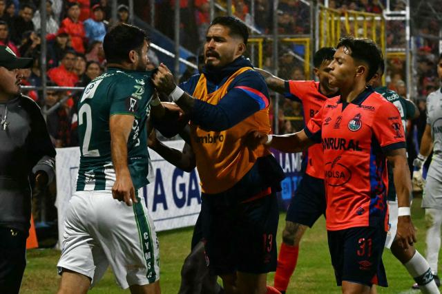 Antigua´s midfielder #13 Dewinder Bradley grabs Antigua´s midfielder #02 Kevin Grijalva at the end of the Guatemalan Apertura tournament final second-leg football match between Municipal and Antigua at El Trebol Stadium in Guatemala City on December 27, 2025. (Photo by JOHAN ORDONEZ / AFP)