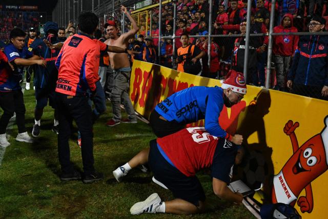 Fans of Municipal fight each other at the end of the Guatemalan Apertura tournament final second-leg football match between Municipal and Antigua at El Trebol Stadium in Guatemala City on December 27, 2025. (Photo by Johan ORDONEZ / AFP)