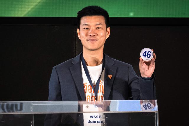 Move Forward Party leader Natthaphong Ruengpanyawut shows the number of his party's draw during the constituencies candidates registration for the upcoming general election, in Bangkok on December 28, 2025. (Photo by Chanakarn Laosarakham / AFP)