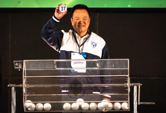 Thailand's Prime Minister and Bhumjaithai Party candidate Anutin Charnvirakul shows the number of his party's draw during the constituencies candidates registration for the upcoming general election, in Bangkok on December 28, 2025. (Photo by Chanakarn Laosarakham / AFP)