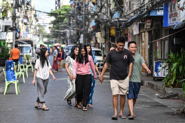 People walk past the entrance of a polling station during the first phase of Myanmar's general election in Yangon on December 28, 2025. (Photo by NHAC NGUYEN / AFP)