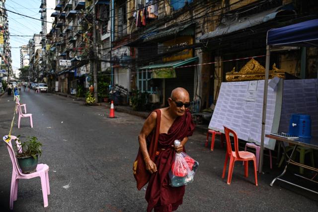 A monk walks on a street past the entrance of a polling station during the first phase of Myanmar's general election in Yangon on December 28, 2025. (Photo by NHAC NGUYEN / AFP)