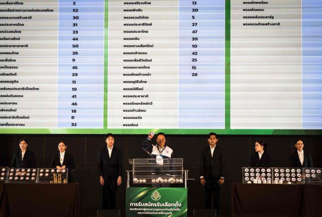 Thailand's Prime Minister and Bhumjaithai Party candidate Anutin Charnvirakul shows the number of his party's draw during the constituencies candidates registration for the upcoming general election, in Bangkok on December 28, 2025. (Photo by Chanakarn Laosarakham / AFP)