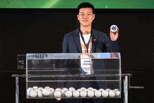 Move Forward Party leader Natthaphong Ruengpanyawut shows the number of his party's draw during the constituencies candidates registration for the upcoming general election, in Bangkok on December 28, 2025. (Photo by Chanakarn Laosarakham / AFP)