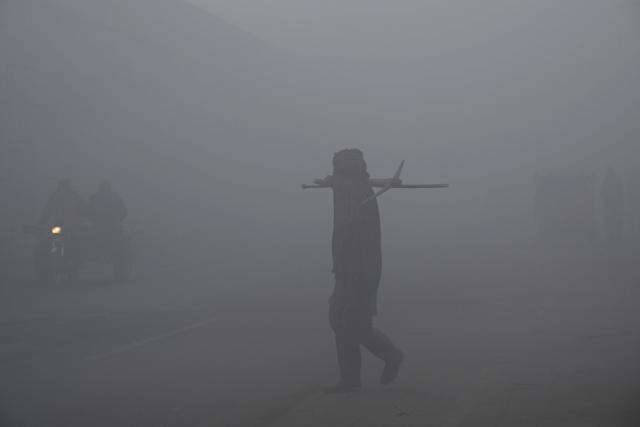 A man walks along a street amid dense smog in Lahore on December 28, 2025. (Photo by Arif ALI / AFP)