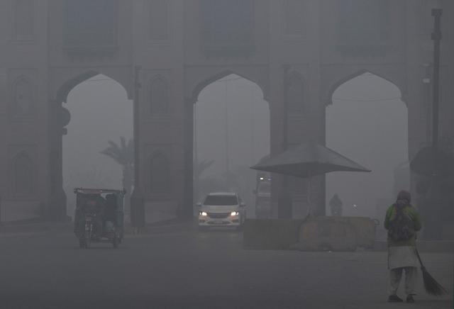 Commuters ride along a street amid dense smog in Lahore on December 28, 2025. (Photo by Arif ALI / AFP)