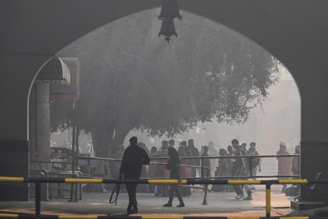 Security personnel stand guard amid dense smog at a railway station in Lahore on December 28, 2025. (Photo by Arif ALI / AFP)