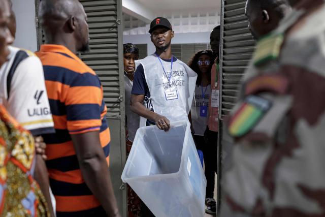 An official of the General Directorate of Elections (DGE) shows an empty ballot box at a polling station in Conakry on December 28, 2025 before polls open during Guinea's presidential election. (Photo by Patrick MEINHARDT / AFP)