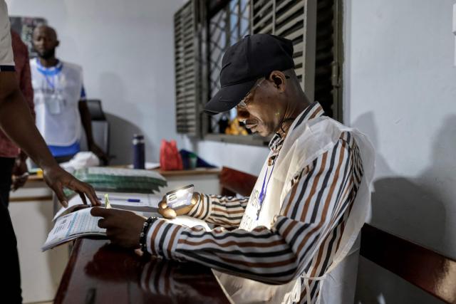 An officials of the General Directorate of Elections (DGE) checks a voter's information at a polling station in Conakry on December 28, 2025 before polls open during Guinea's presidential election. (Photo by Patrick MEINHARDT / AFP)