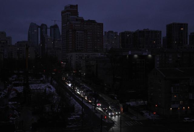 This photograph shows vehicles with headlights driving down a non-illuminated street during a power outage in Kyiv on December 27, 2025, following Russian missile and drone attacks on Ukrainian energy infrastructure amid the Russian invasion of Ukraine. (Photo by Sergei SUPINSKY / AFP)