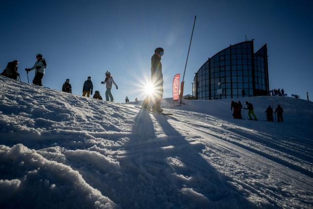 Tourists are seen in silhouette on a ski slope next to the Kuklos mountain restaurant above the low-altitude resort of Leysin on December 27, 2025. (Photo by Fabrice COFFRINI / AFP)