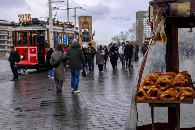 A street vendor sells traditional Turkish bagels "Simit" as he waits for customers at Taksim Square, in Istanbul, on December 27, 2025. Simit roams the streets of Turkey as surely as cats. But the price of this small, round, ring-shaped bread, studded with sesame seeds, is also a stark indicator of the dizzying price increases. (Photo by Yasin AKGUL / AFP)