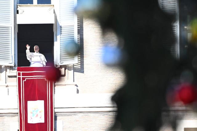 Pope Leo XIV waves to the crowd from the window of the apostolic palace overlooking St. Peter's square during the Angelus prayer in The Vatican on December 28, 2025. (Photo by Andreas SOLARO / AFP)