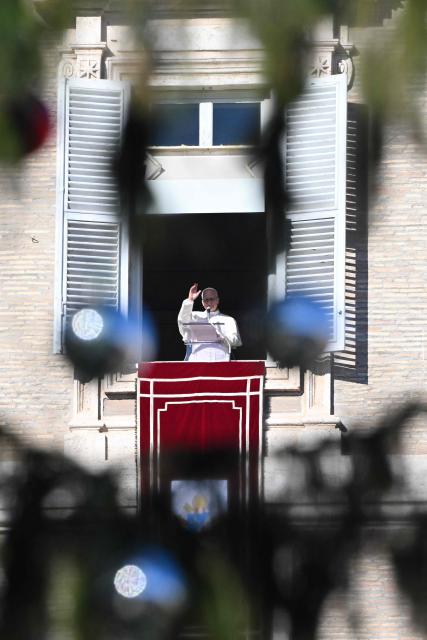 Pope Leo XIV blesses the crowd from the window of the apostolic palace overlooking St. Peter's square during the Angelus prayer in The Vatican on December 28, 2025. (Photo by Andreas SOLARO / AFP)