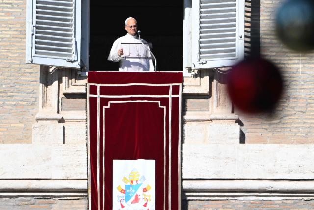 Pope Leo XIV looks to the crowd from the window of the apostolic palace overlooking St. Peter's square during the Angelus prayer in The Vatican on December 28, 2025. (Photo by Andreas SOLARO / AFP)