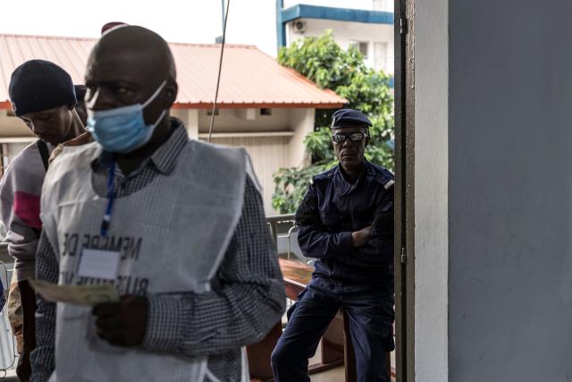 A Guinea police officer stands guard as voters queue at a polling station in Conakry on December 28, 2025 during Guinea's presidential election. (Photo by PATRICK MEINHARDT / AFP)