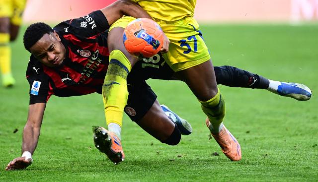AC Milan's French forward #18 Christopher Nkunku (down) fights for the ball with Hellas Verona's German defender #37 Armel Bella-Kotchap during the Italian Serie A football match between AC Milan and Hellas Verona at the San Siro stadium in Milan, northern Italy, on December 28, 2025. (Photo by Piero CRUCIATTI / AFP)