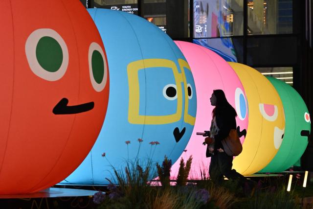 A woman walks past a shopping mall in Beijing on December 28, 2025. (Photo by ADEK BERRY / AFP)